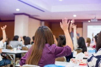 business people raise their hands to vote for shareholders' meeting or seminar event in the meeting room. participants are raising their hands to ask questions. vote for democratic. selective focus.