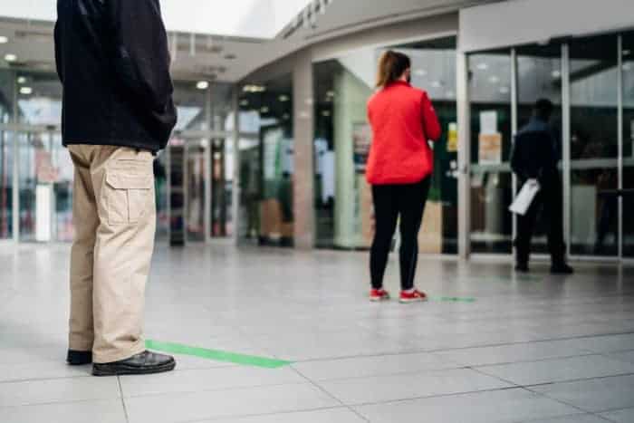 People standing in line front of bank/store due to coronavirus pandemic safety guideline.COVID-19 safe social distancing practice.Quarantine financial crisis,banking,loans.Spaced out queue.Crowd-limit