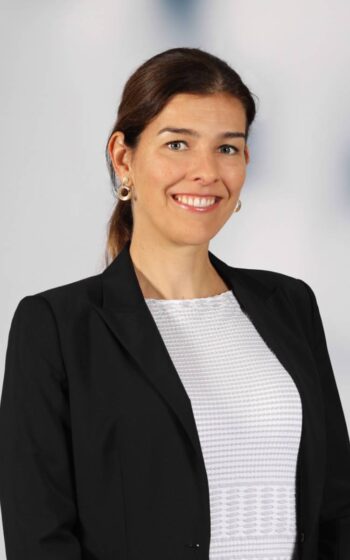 Angela Schmitz-Axe, Director bei Deloitte Consulting, präsentiert sich in professioneller Kleidung. Ihr Lächeln und die aufrechte Haltung reflektieren Selbstbewusstsein. Im Kontext des Innovations-Managements deutscher Banken ist ihre Rolle von Bedeutung.