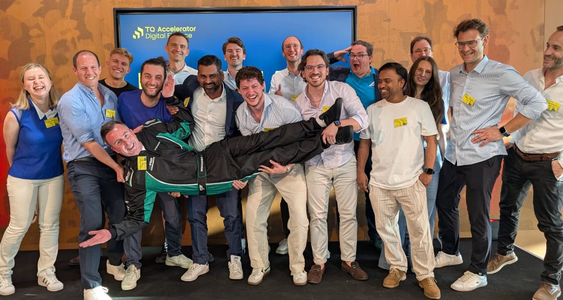 TechQuartier Accelerator Teamfoto vor Bildschirm mit TQ Accelerator Logo.